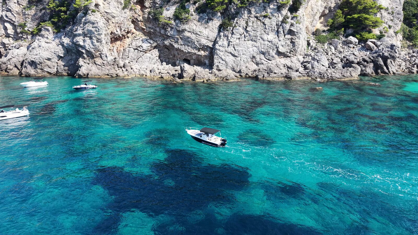 Private boat over vivid turquoise water below the cliffs near the three caves