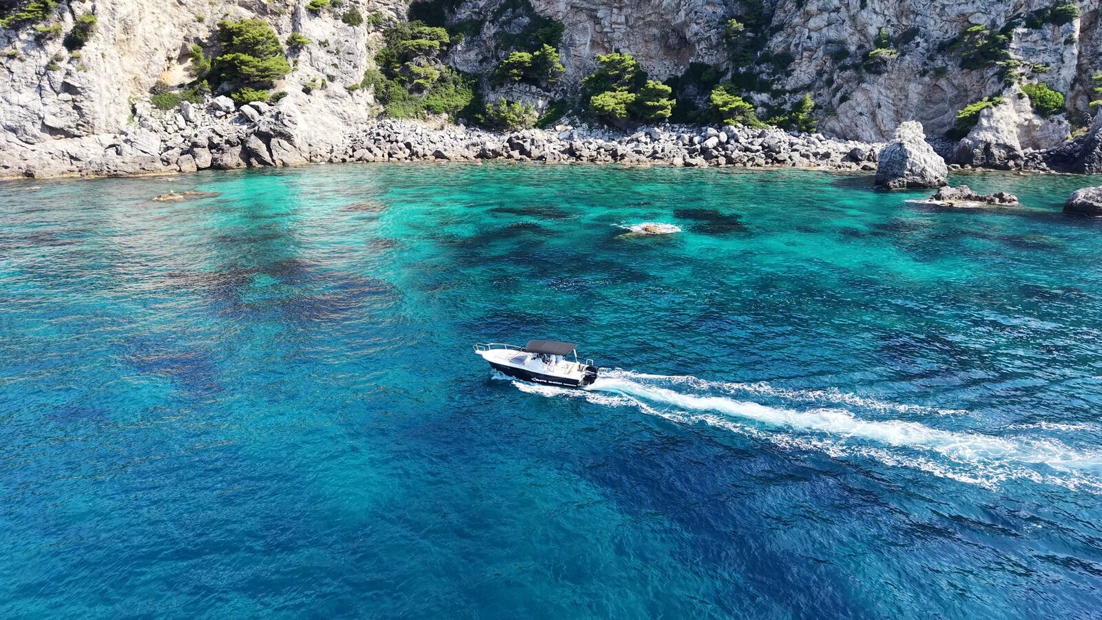 Private boat cruising past dramatic limestone cliffs and caves in clear Adriatic water